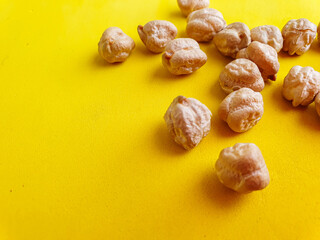 Uncooked dried chickpeas on yellow background. Heap of legume chickpeas background 