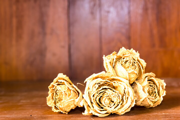 Dry roses on wooden background vintage and retro color tone. 