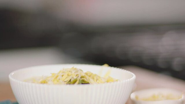 Grated Cheese Falling Onto a Bowl of Food