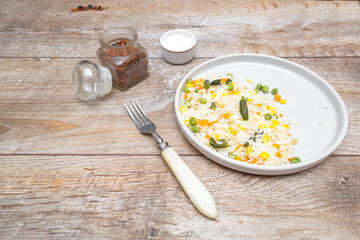 Risotto with vegetables and spices served on gray plate with fork. Homemade food on wooden background. top view, copy space