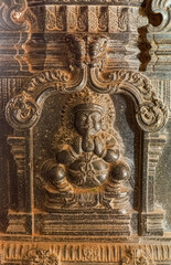 Hampi, Karnataka, India - November 4, 2013: Hazara Rama Temple. Black rock sculpture of squatting man holding coconut between hand palms.