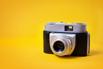 Old retro cine-film photo camera on pastel yellow background