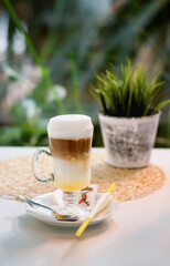 A layered natural caffe latte with syrup in a clear cup.
