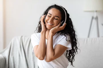 Poster Happy young woman in wireless headphones listening to music © Prostock-studio