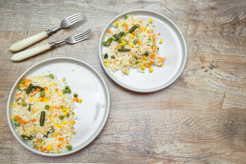 Vegetarian homemade risotto with vegetables served on plates with forks on wooden table with copy space. Rustic food background. Minimal style.