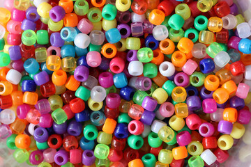 Fototapeta na wymiar Multicolored plastic beads for handicraft are scattered on the table