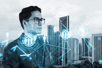 Handsome eastern HR director at international company thinking about efficient strategy to recruit highly qualified specialists. Social media and marketing hologram icons over Kuala Lumpur background