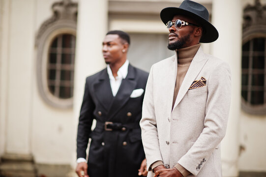 Two fashion black men. Fashionable portrait of african american male models. Wear suit, coat and hat.