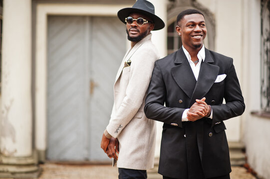 Two fashion black men. Fashionable portrait of african american male models. Wear suit, coat and hat.