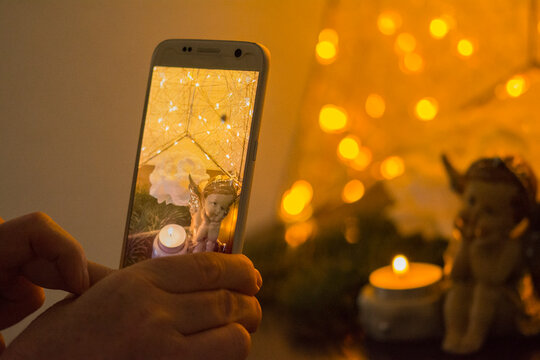 Handy fotografiert Kerze und Engel im Kerzenlicht