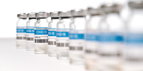 Panoramic photo of a lot ampoules with COVID-19 corona virus vaccine for injection on white background. Coronavirus vaccine manufacture, worldwide vaccination and healthcare concept