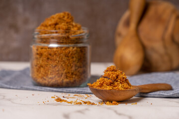 shredded chicken served in a glass jar and wooden spoon.