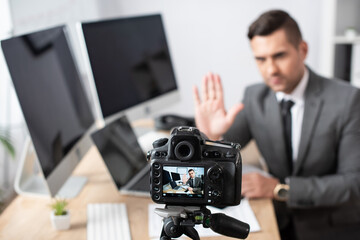 selective focus of digital camera near trader waving hand on blurred background