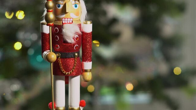 Wooden Nutcracker doll in front of sparkling Christmas tree