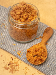 shredded chicken served in a glass jar and wooden spoon.