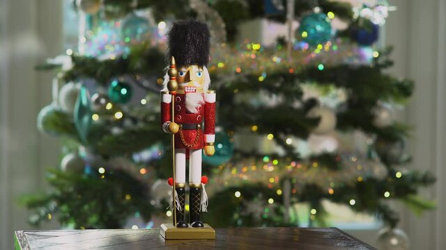 Wooden Nutcracker doll in front of sparkling Christmas tree