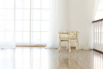 Luxury stylish bright light interior of sitting room. White walls decorated by ornament. Fireplace. Nobody inside room. Table setting by dishes, candles and flower bouquets.