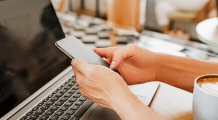 Happy business man sitting at cafeteria with laptop and smartphone. Businessman texting on smart phone while sitting in a cafe, working and checking email on computer