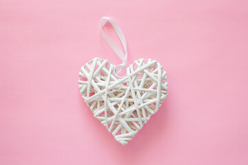 Wicker white heart on pink background. Valentine's day and love romantic concept with copy space for text.