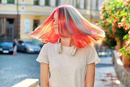 Close-up of fluttering colored dyed hair of young woman on sunny city street