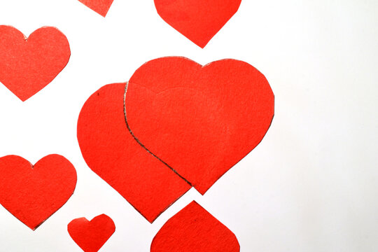 Chaotically scattered symbols of love of the heart lie on a white sheet, the right side of the sheet is free. High quality photo - Powered by Adobe