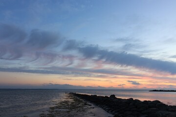 Scenic seascape with rock groyne and clouds at dawn