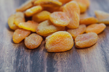 Dried apricots lie on a wooden board.