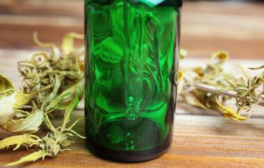 Macro close up of green isolated dropping pipette medical cannabinol cpd oil bottle with dried cannabis buds on wood table)