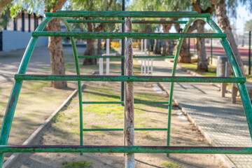 Close-up of a green vintage metal swing located in a park