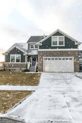 A modern dark gray and white new construction craftsman with stone accents and a purple front door...