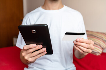 Male person doing online shopping with his tablet and paying with credit card