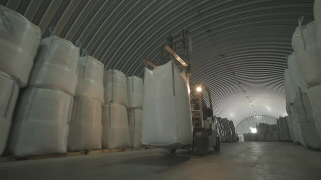 Warehousing. Forklift driver stacking big bag of raw material in warehouse.
