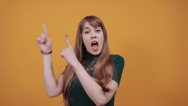 Hand points index finger up, pointing forefinger surprise gift option, great idea. Young attractive woman, dressed green shirt blonde hair, yellow background