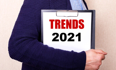TRENDS 2021 is written on a white sheet held by a man standing sideways