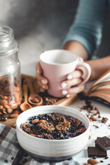 Healthy breakfast, muesli with berries and orange juice served on glass table and books. manicure