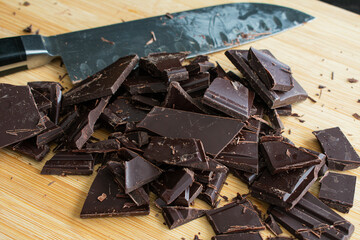 Chopping Bars of Baking Chocolate: Using a kitchen knife to cut two dark chocolate bars into pieces