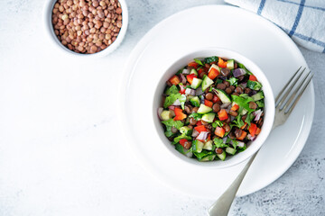 Green lentil red bell pepper cucumber parsley salad in a bowl