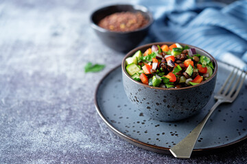 Green lentil red bell pepper cucumber parsley salad in a bowl