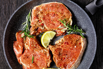 raw pork chops on a skillet, top view