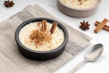 Creamy rice pudding with cinnamon in bowl on white marble table