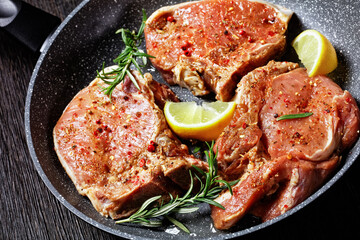 raw pork chops on a skillet, top view