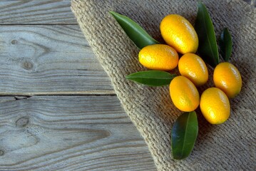 Fresh kumquats on a wooden table. Citrus background.