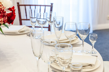 Fancy table set for dinner with napkin glasses in restaurant, luxury interior background. Wedding elegant banquet decoration and items for food arranged by catering service on white tablecloth table.