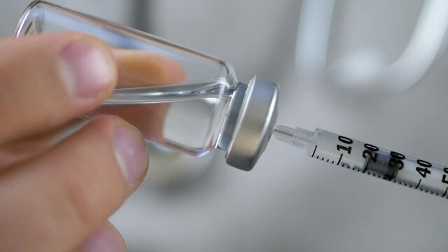 Doctor or nurse dials the vaccine. Medical vials for injection with syringe and needle. Vaccination immunization, medical injection