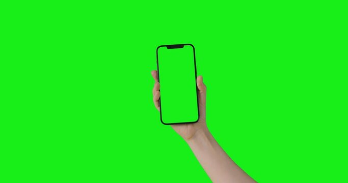 Woman hand holding the smartphone on green screen chroma key background.  Phone mock-up for your product. The iPhone 12 Pro Max model in vertical orientation portrait mode.