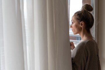 A sad woman is looking out the window. Sadness and depression.