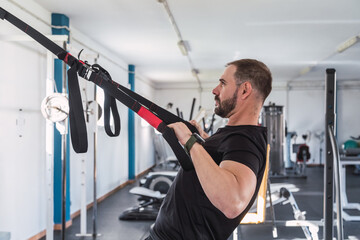 Young man doing TRX exercises at the gym. TRX training. Sport and fitness. Crossfit workout