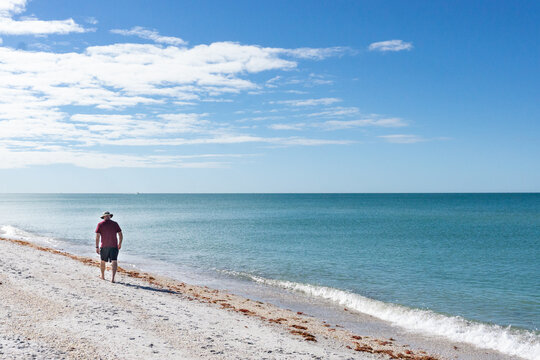 60 year old man walks along beach in Florida