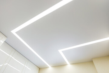 suspended ceiling with halogen spots lamps and drywall construction in empty room in apartment or house. Stretch ceiling white and complex shape. - obrazy, fototapety, plakaty
