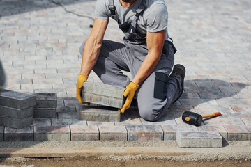 Concentrated at work. Man in yellow colored uniform have job with pavement